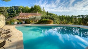 Une piscine avec une maison en arrière-plan, le tout entouré d’une végétation luxuriante.
