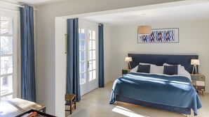 Une chambre à coucher avec un lit, un bureau, une chaise, une lampe et une fenêtre avec des rideaux.