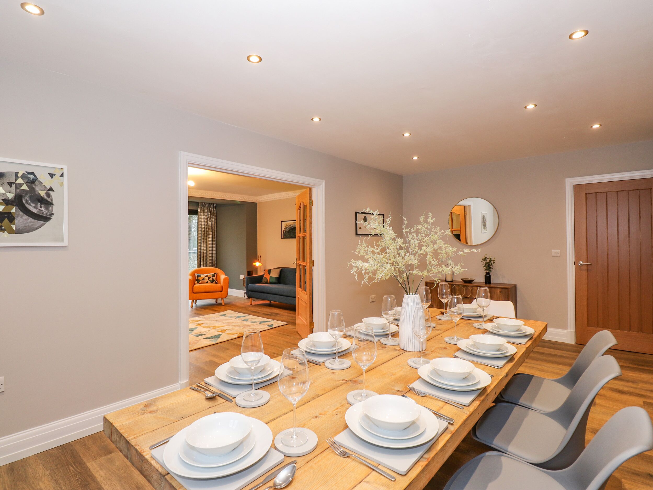Comedor con una larga mesa de madera dispuesta para seis personas, rodeado de sillas modernas.