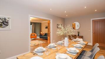 Comedor con una larga mesa de madera dispuesta para seis personas, rodeado de sillas modernas.