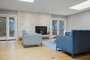 A modern living room with a fireplace, two sofas, and a large window.