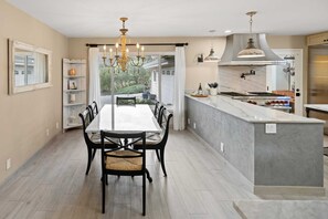 A modern kitchen with a central island, pendant lighting, and a dining area with a view. - Deer Meadow 4BR 3Ba w Valley Views 30 Night Min (Carmel Valley)