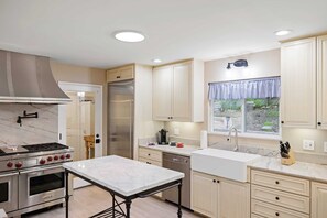 A modern kitchen with a built-in stove, oven, and refrigerator, a marble countertop, and light-colored cabinetry. - Deer Meadow 4BR 3Ba w Valley Views 30 Night Min (Carmel Valley)