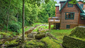 Een chalet met terras, met uitzicht op een bebost gebied en een beek.