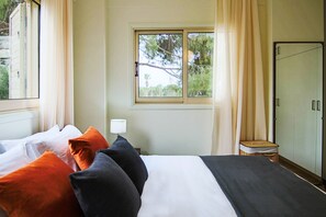 Une chambre d’hôtel avec un lit, une fenêtre avec des rideaux, une lampe de chevet et une armoire.