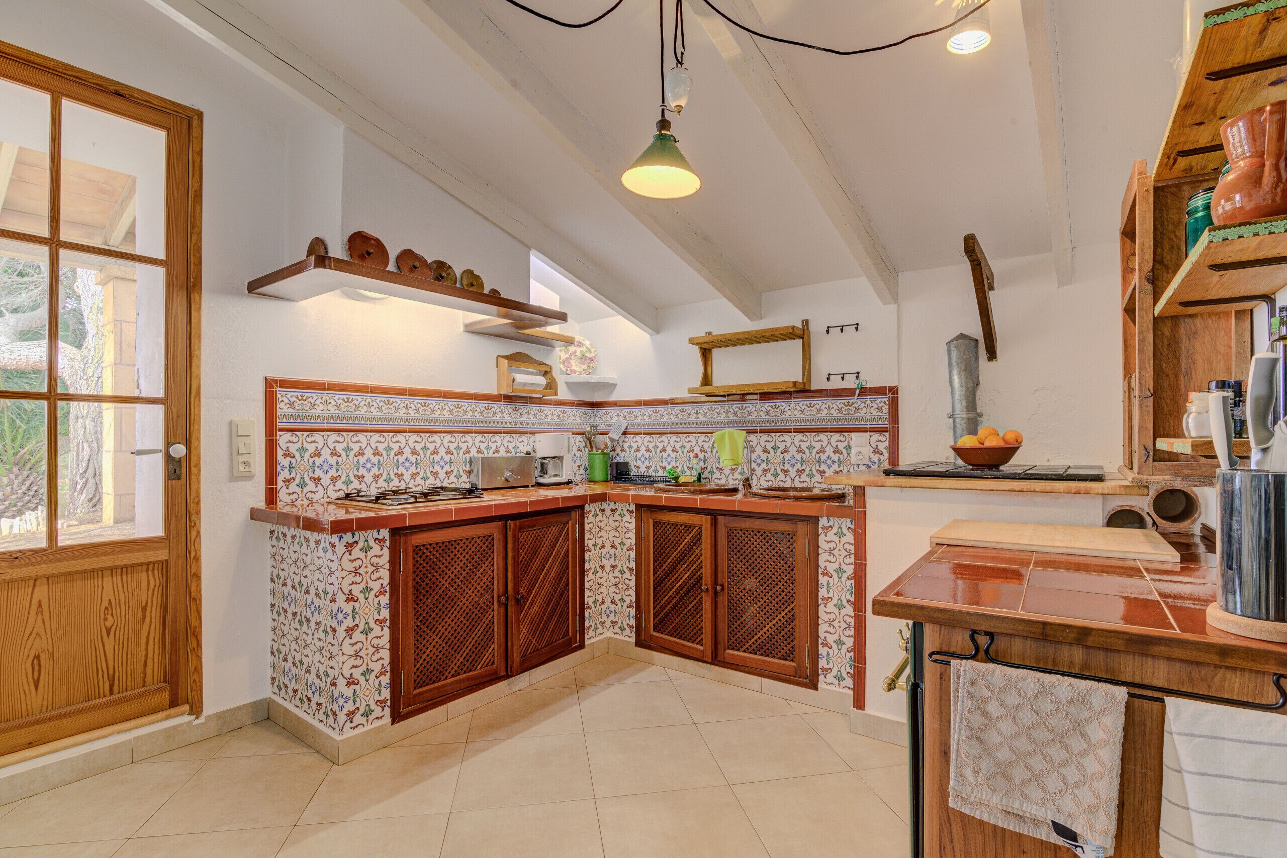 Una cocina con armarios de madera, salpicadero de azulejos y una lámpara colgante.