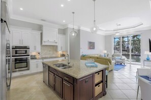 A modern kitchen with white cabinetry, granite countertops, and stainless steel appliances.