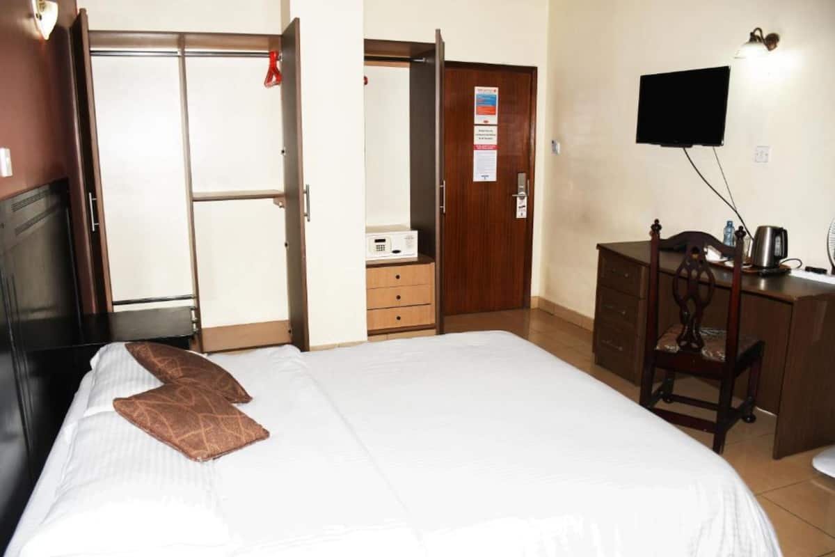A hotel room with a bed, a dresser, a television, and a desk.