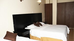 A hotel room with two beds, a wardrobe, and a nightstand. - Jamia Central Hotel (Nairobi)