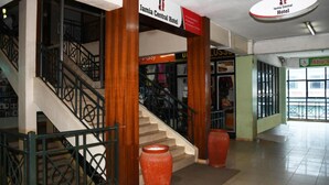 A hotel lobby with a staircase, a large vase, and a sign for Jamia Central Hotel. - Jamia Central Hotel (Nairobi)