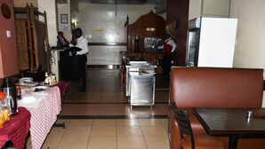 A restaurant with a counter, tables, and a seating area. - Jamia Central Hotel (Nairobi)