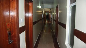 A hallway with wooden doors and white walls. - Jamia Central Hotel (Nairobi)