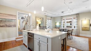 A modern kitchen with a central island, wooden flooring, and a dining area with a table and chairs.
