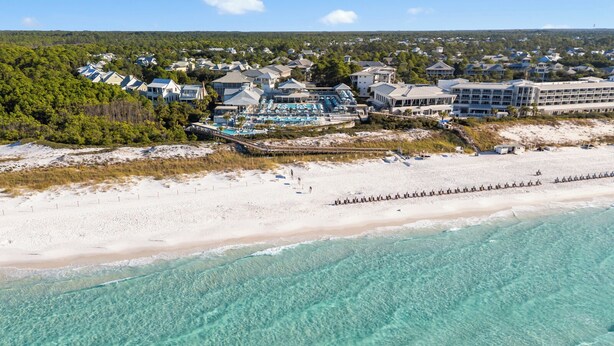 Une station balnéaire dotée de villas en bord de mer, d’un espace piscine et d’une plage de sable.