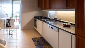 A modern kitchen with wooden cabinets, a black countertop, and a tiled backsplash. - Quinta do Mar - Watch The Sun Rise Over The Ocean (Angra do Heroismo)