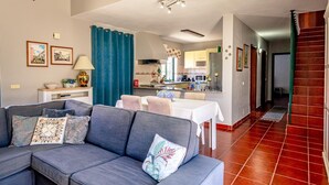 Un soggiorno moderno con un divano grigio, un tavolo da pranzo e un angolo cottura sullo sfondo.