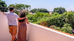 Una coppia in piedi su un balcone con vista su un giardino e uno specchio d'acqua.