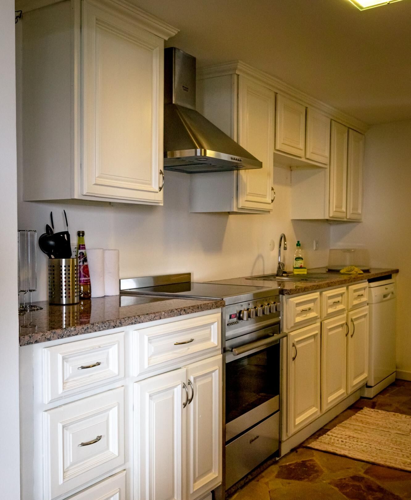 Una cocina con armarios blancos, electrodomésticos de acero inoxidable y encimera de granito.