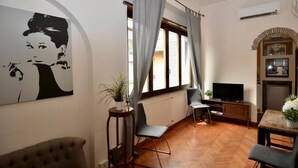 A living room with a television, two chairs, a sofa, a potted plant, and a large abstract painting on the wall. - Piazza Navona Penthouse - Piazza Navona Penthouse (Rome)