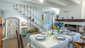 A dining area with a table set for four, a staircase, and a fireplace. - Casa Ciculino 8 (Monteleone d'Orvieto)
