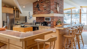 Una cocina moderna con una isla central, una chimenea de ladrillo y un amplio ventanal que ofrece luz natural.
