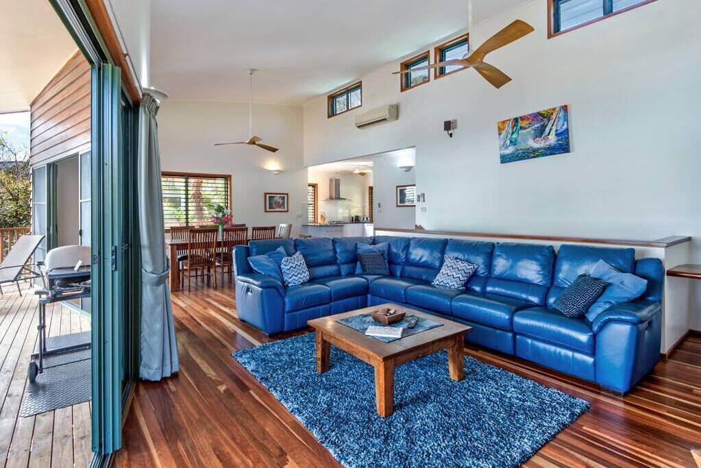 A spacious living area with a blue sectional sofa, a wooden coffee table, and a sliding glass door leading to an outdoor deck.