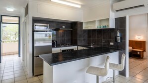 A modern kitchen with a central island, bar stools, a built-in oven, and a microwave.