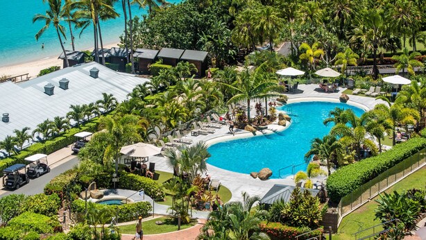 A resort with a pool, palm trees, and a beach.