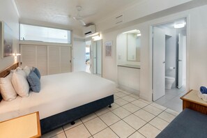 A bedroom with a bed, bedside table, and a view of the balcony. - Whitsunday Apartment West 402 (Hamilton Island)