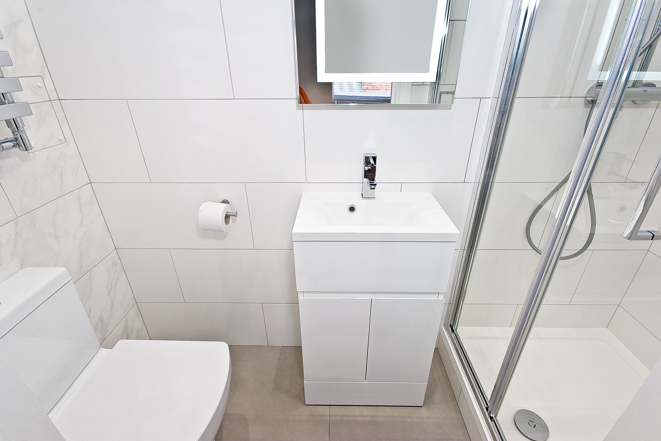 Un baño moderno con lavamanos, inodoro y ducha blancos.