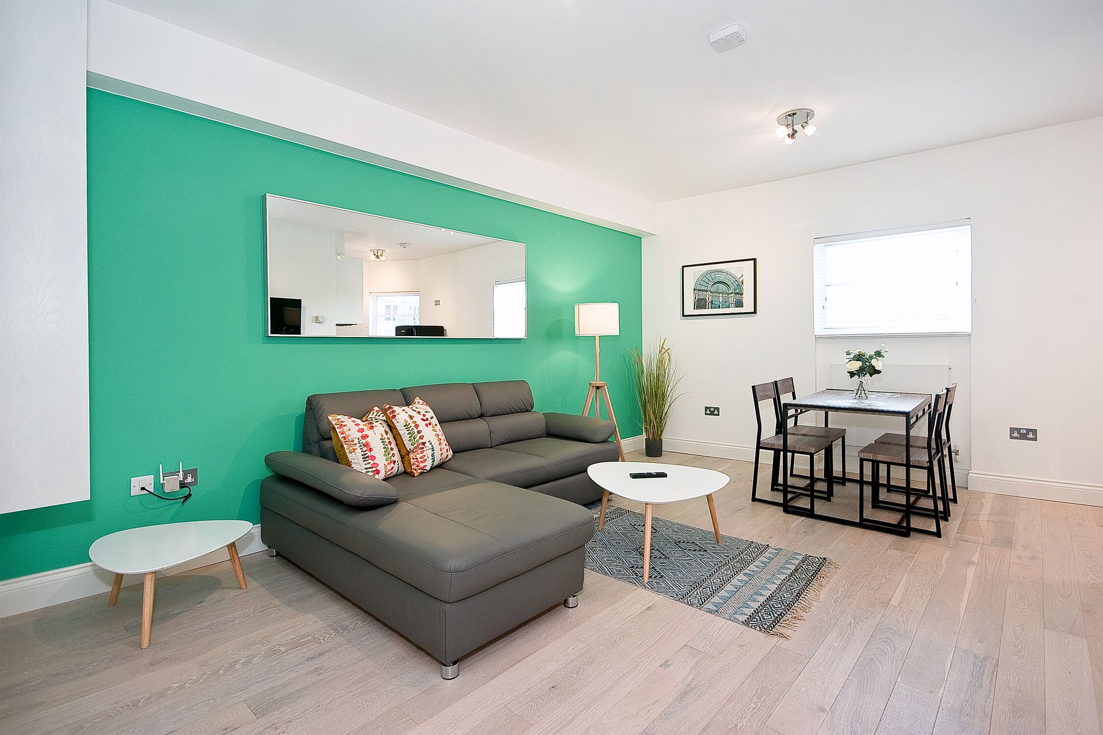 A modern living room with a sectional sofa, a small white table, and a dining area with chairs and a table.