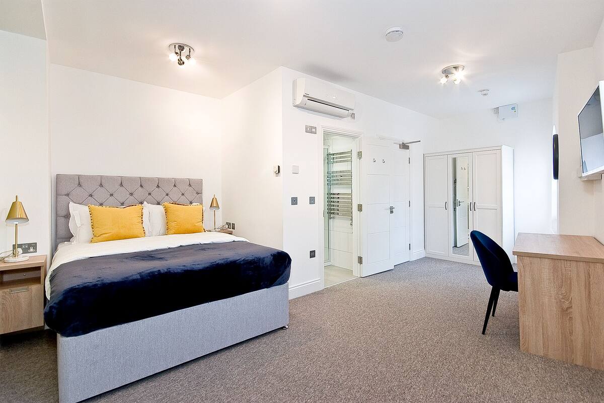 Una habitación de hotel moderna con una cama grande, un escritorio y un armario.