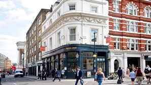 A street view with a building labeled "The Real Greek" and another building with "Garden House" signage. - Interlude House by City Living London (London)