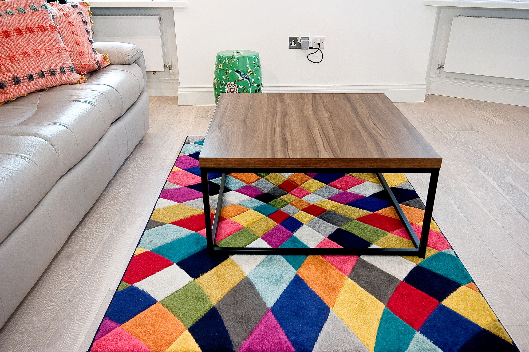 Una sala de estar moderna con un sofá de cuero, una mesa de centro de madera y un tapiz geométrico colorido.