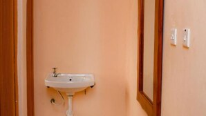 A narrow hallway with a white sink mounted on the wall, a wooden door frame, and a mirror on the right wall. - Faraja Guest House (Naivasha)
