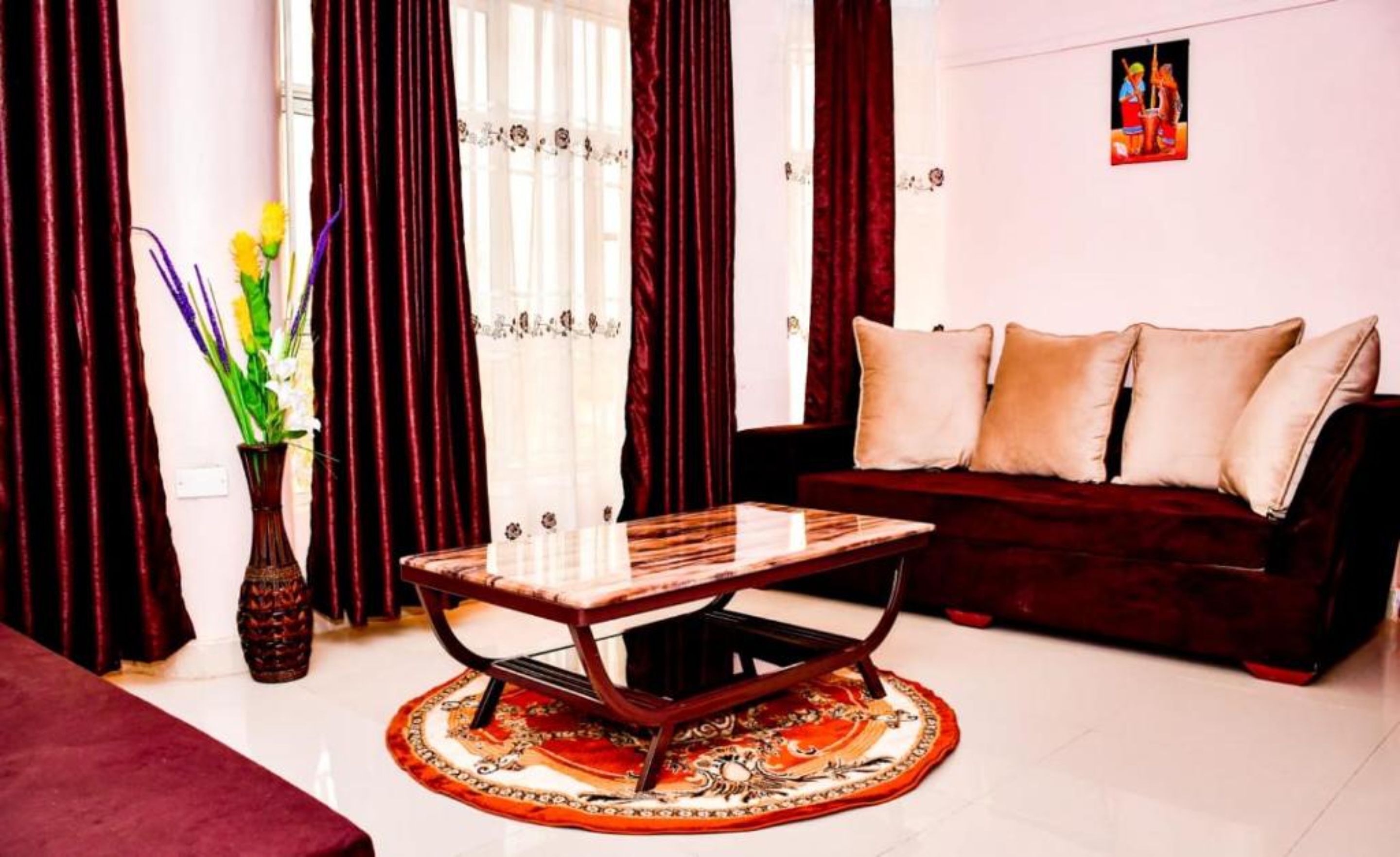 A living room with a dark red sofa, a wooden coffee table, and a patterned rug.