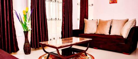 A living room with a dark red sofa, a wooden coffee table, and a patterned rug.