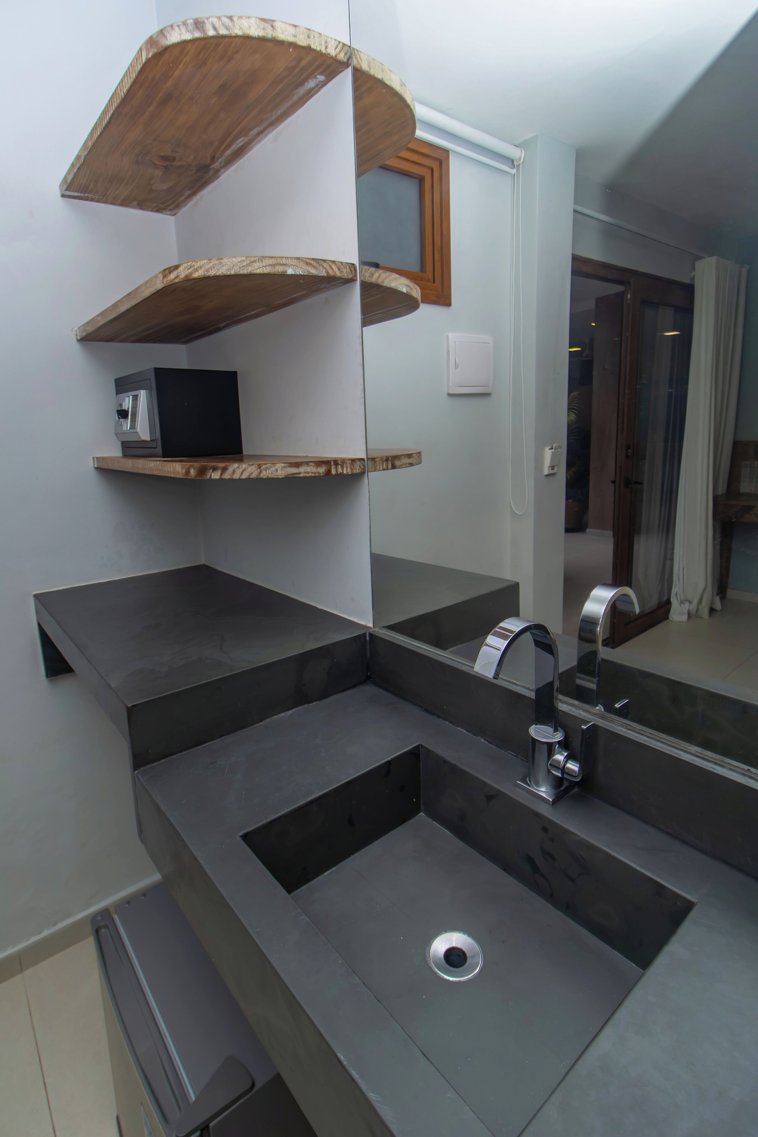 Un baño moderno con un espejo grande, un lavabo y estantes de madera.