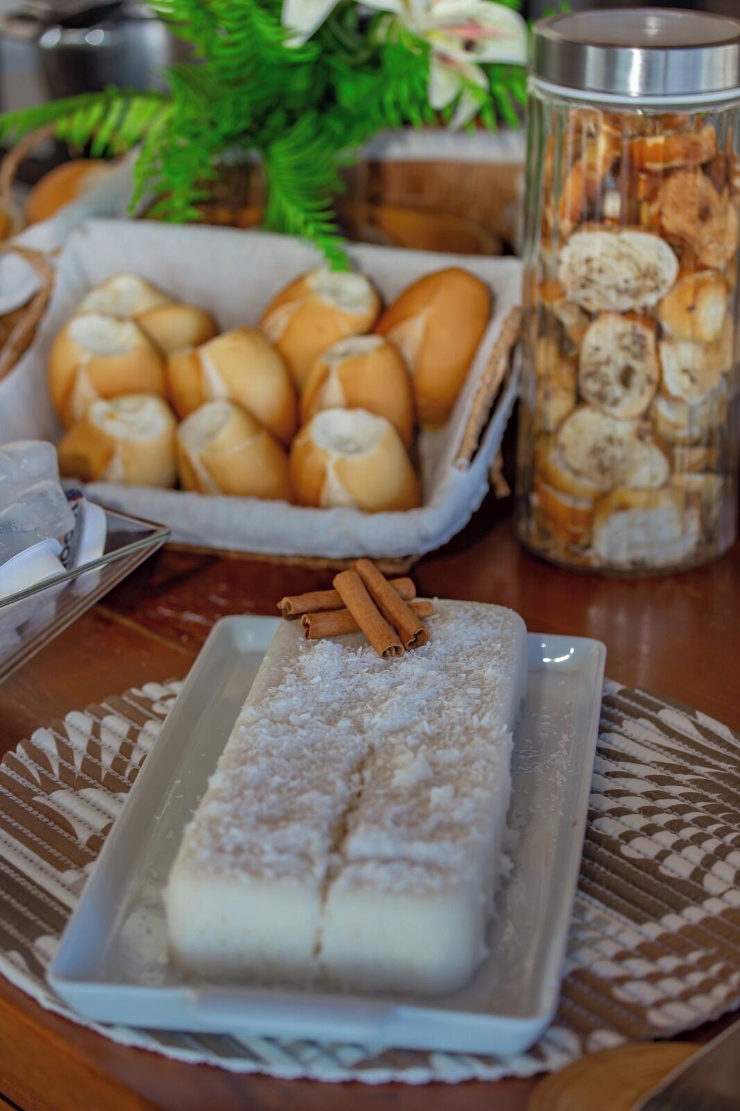 Un plateau de desserts comprenant un gâteau rectangulaire, un bocal de biscuits et un panier de petits pains.