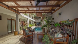 A covered outdoor area with a pool, wooden furniture, and various plants. - Terra Bella Pousada (Cairu)