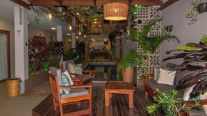 A lobby with wooden furniture, a central seating area, and potted plants. - Terra Bella Pousada (Cairu)