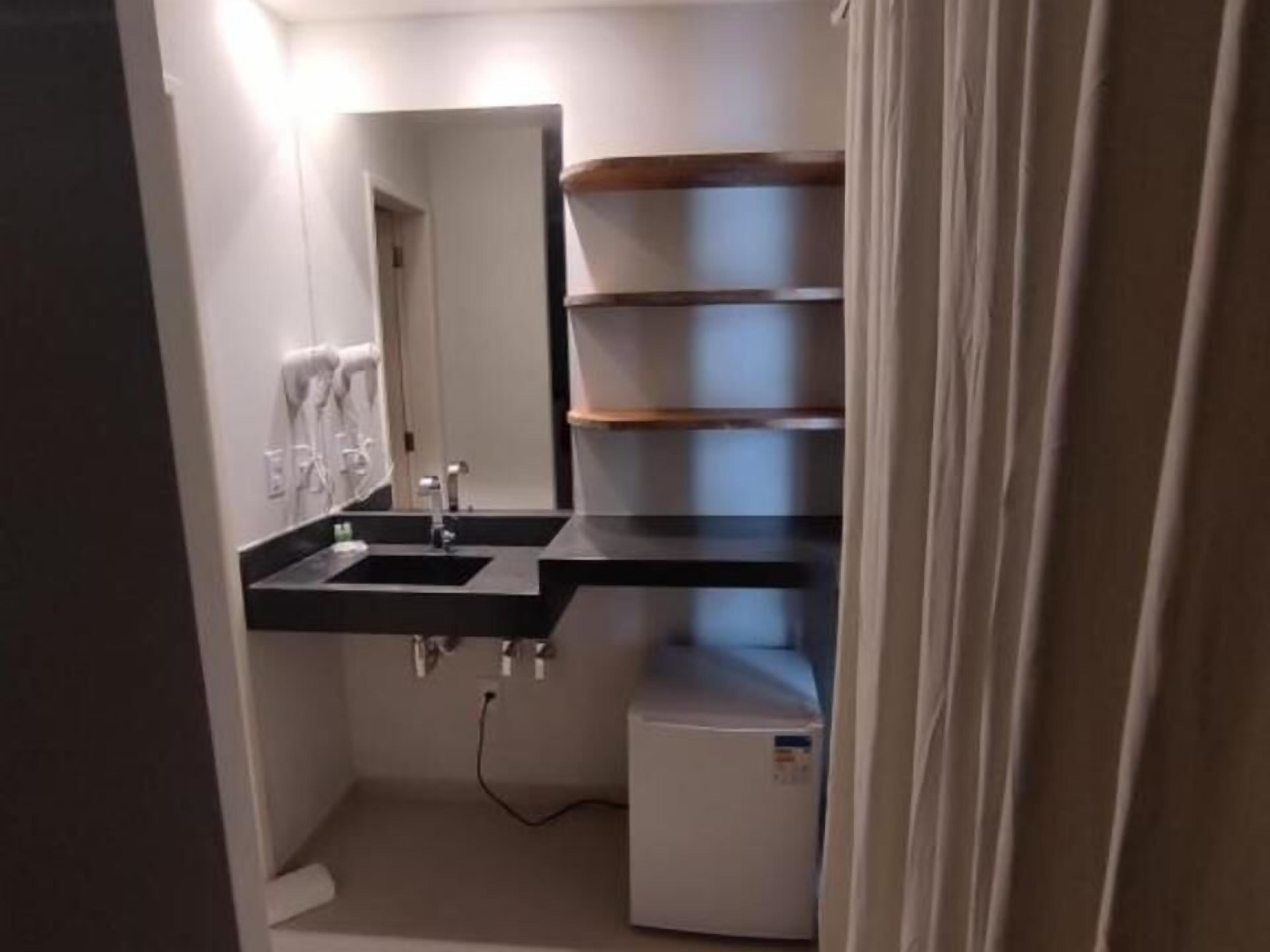 A compact bathroom with a sink, mirror, and a small white appliance, likely a heater or air purifier.