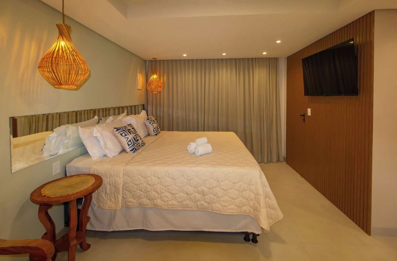 A hotel room with a large bed, two wall-mounted lamps, a flat-screen TV, and a wooden wardrobe.