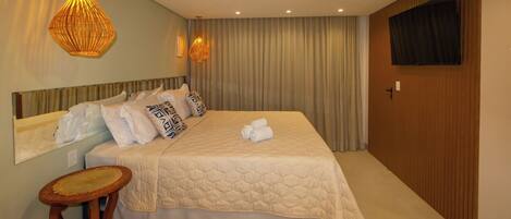 A hotel room with a large bed, two wall-mounted lamps, a flat-screen TV, and a wooden wardrobe.