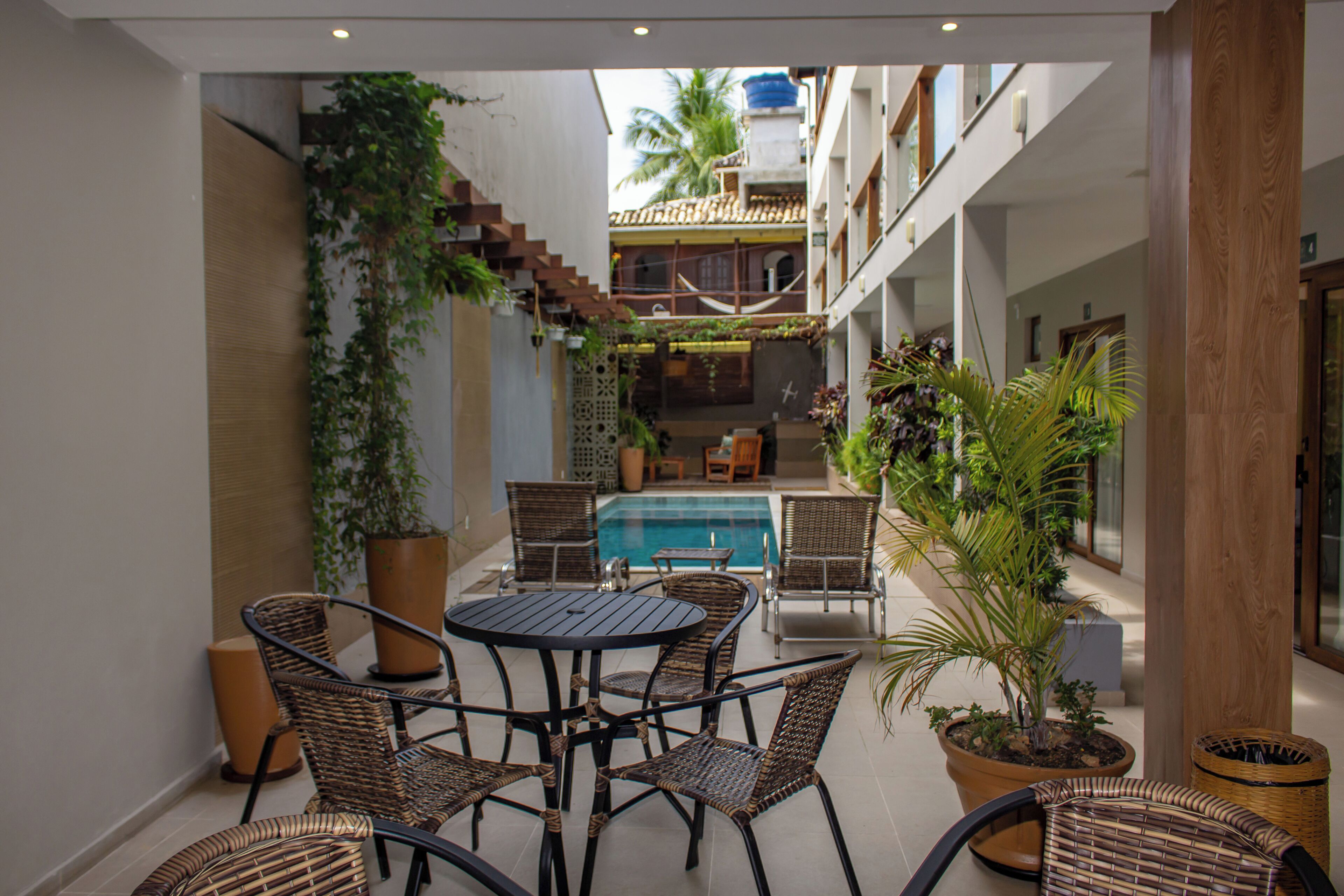 A poolside area with wicker furniture and potted plants.
