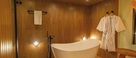 Un baño moderno con una bañera independiente, paredes de paneles de madera y suelo de madera.