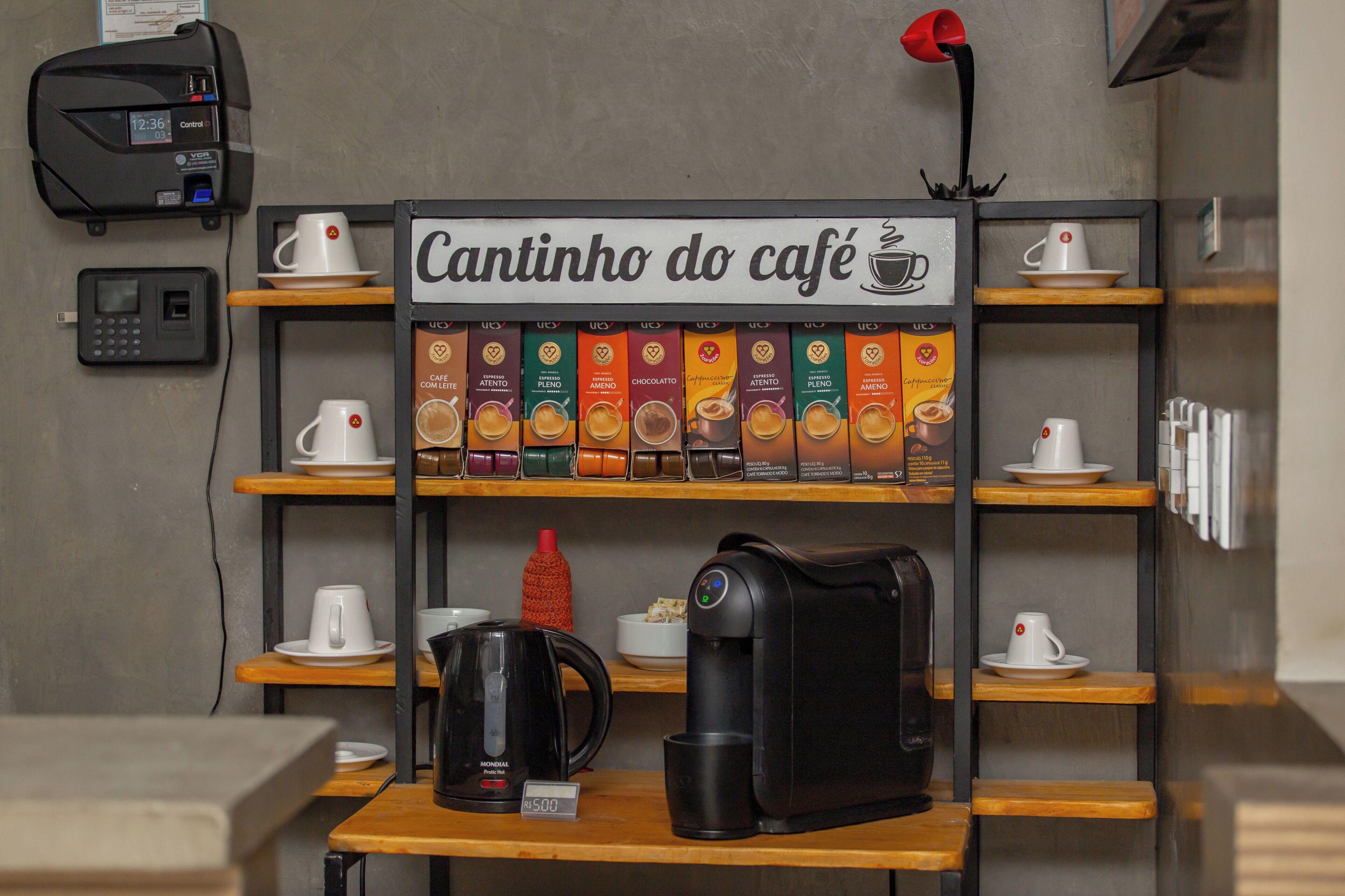A coffee shop interior with a coffee machine, a selection of coffee pods, and a sign reading 'Cantinho do café'.