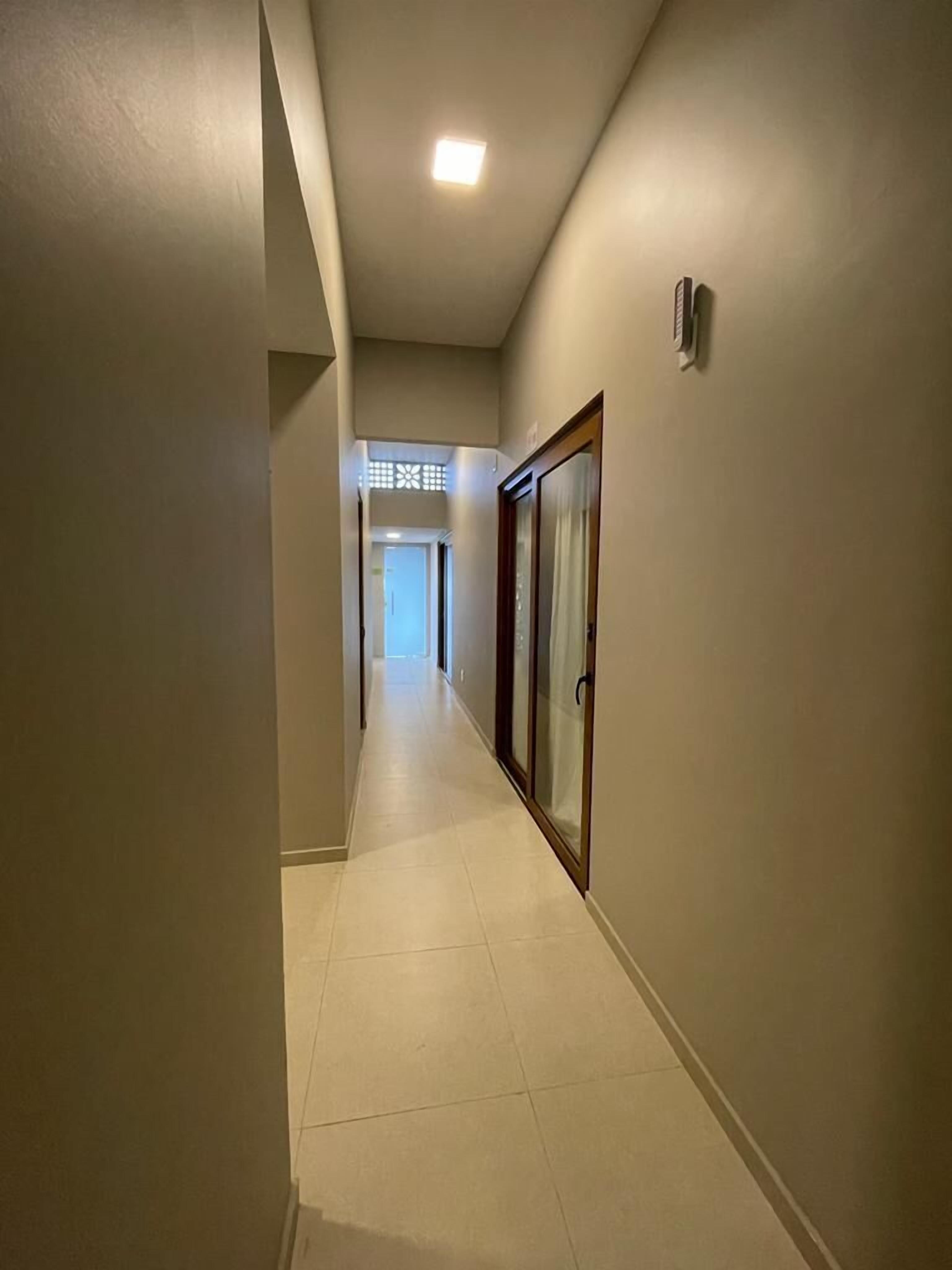 A hallway with a tiled floor, a door with a glass panel, and a ceiling light.