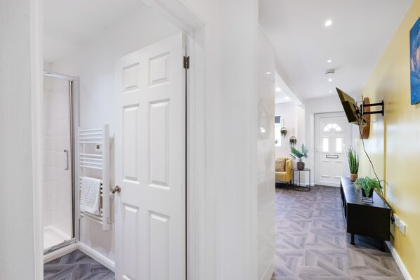 Experience the sleek design of this stylish hallway, featuring a glass door to a shower area and a console table with potted plants.