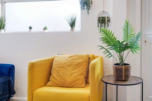 Relax in a serene space with a comfortable armchair, a small table, and a potted plant, offering a view of the outdoors.
